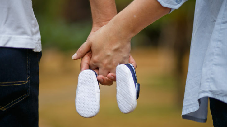 man-woman-holding-hands-baby-shoes